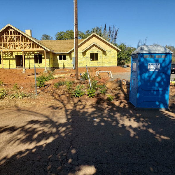 house under construction with a blue construction porta potty in the front yard for the contractors
