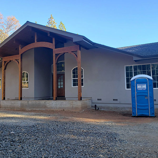 blue construction porta potty outside newly built house